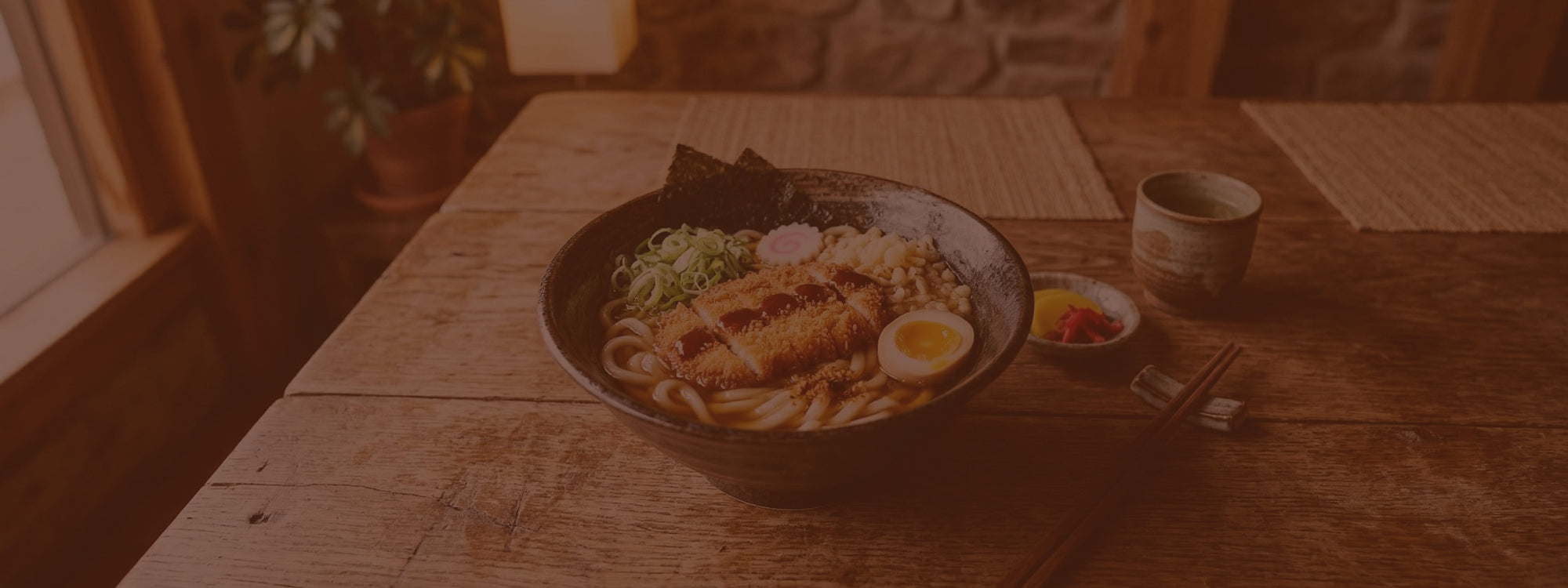 Bowl of ramen with toppings on a wooden table in a cozy setting