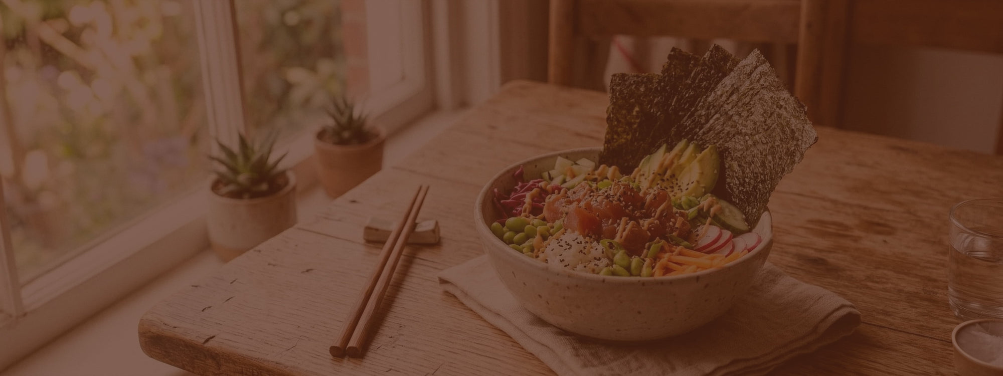 Bowl of salad with crackers and chopsticks on a wooden table