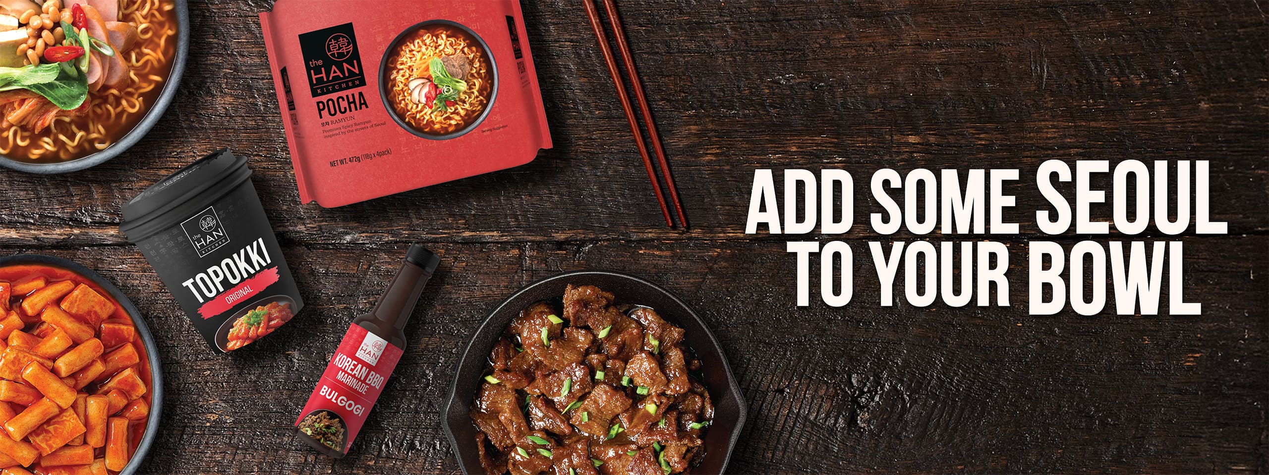 The Han Kitchen food products including ramyun, marinades and Topokki on a wooden surface with text that reads "Add some Seoul to your bowl".