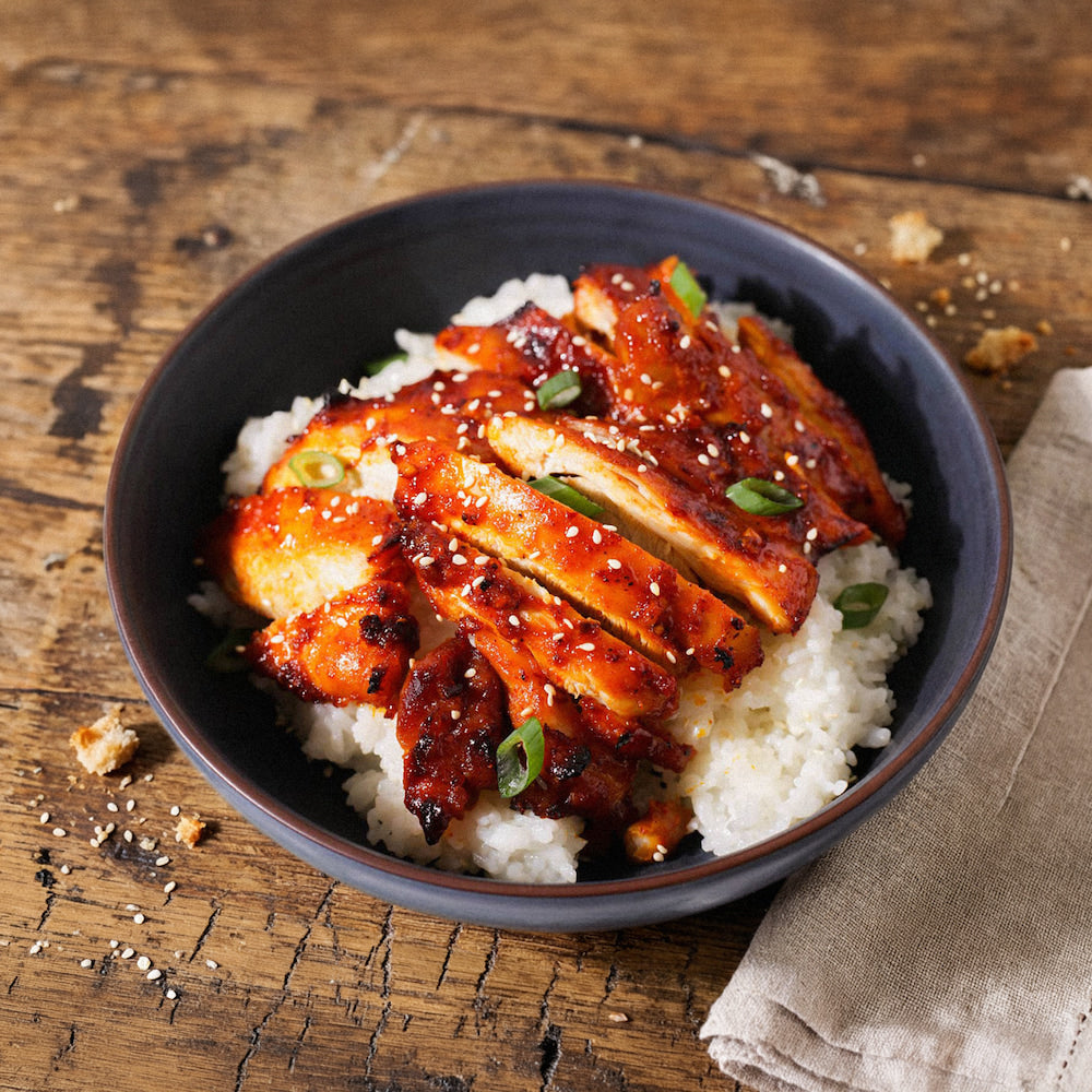 Bowl of rice with teriyaki chicken on a wooden table